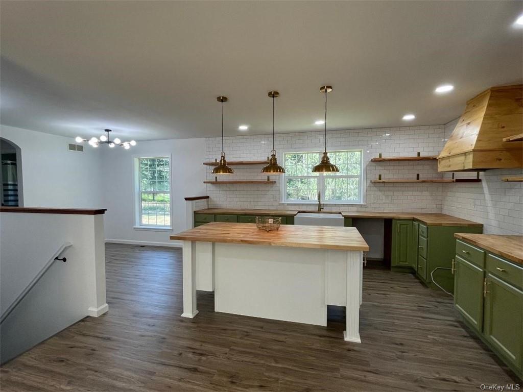 a kitchen with kitchen island wooden floors appliances and cabinets