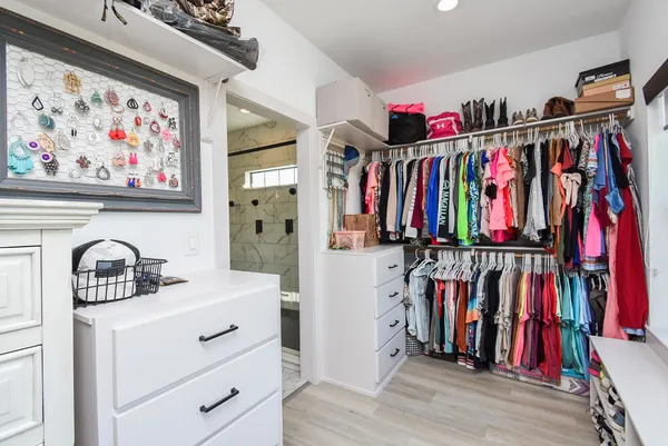a view of walk in closet with clothes and shoes