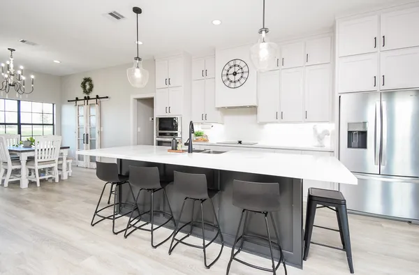 a kitchen with stainless steel appliances kitchen island granite countertop a dining table chairs and white cabinets