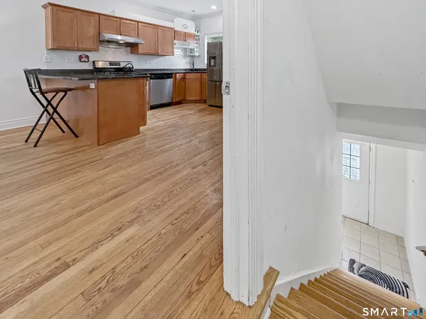 a kitchen with stainless steel appliances granite countertop a stove a sink dishwasher and a refrigerator with wooden floor