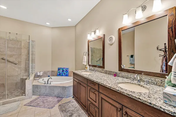 a bathroom with a granite countertop sink a mirror a bathtub and shower