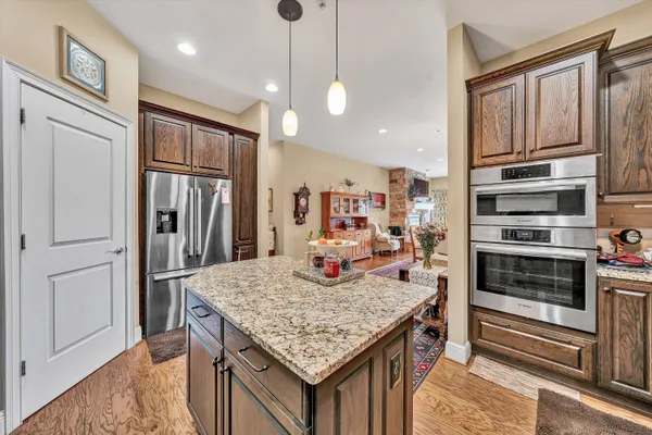 a kitchen with stainless steel appliances granite countertop a kitchen island hardwood floor and a refrigerator