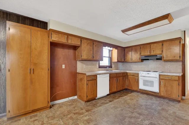 a kitchen with stainless steel appliances granite countertop a refrigerator a sink dishwasher stove and oven