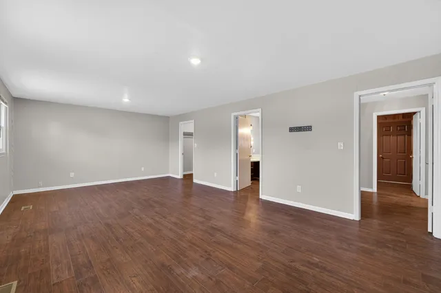 a view of an empty room with wooden floor and closet
