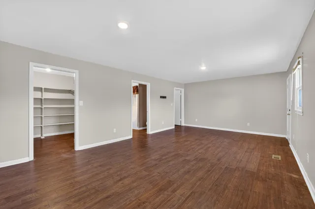 a view of an empty room with wooden floor and closet