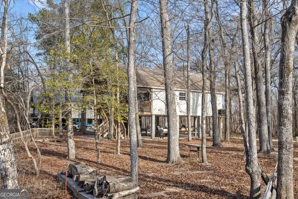 a view of a brick house with large trees and wooden fence