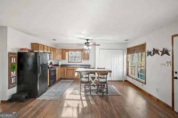 a kitchen with stainless steel appliances a dining table chairs refrigerator and cabinets