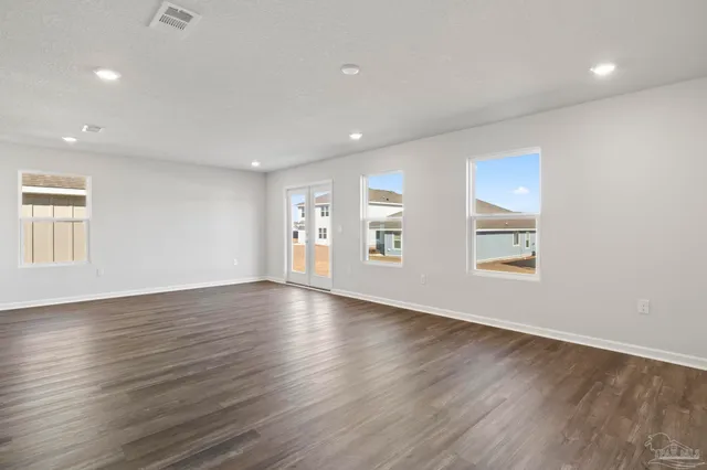 a view of an empty room with window and wooden floor