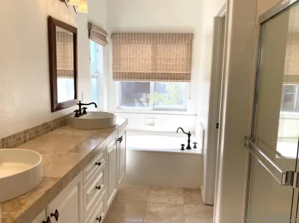a bathroom with a granite countertop sink and a bathtub next to a window
