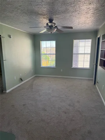 an empty room with a windows and ceiling fan