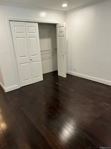 an empty room with wooden floor cabinet and windows
