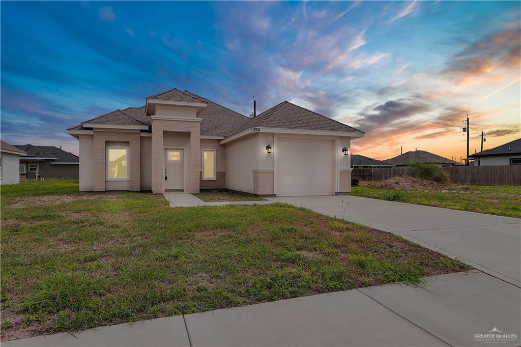824 Lark Street Alamo, TX 78516 - Photo 2 of 17 View of front of home featuring a shingled roof, an attached garage, driveway, and stucco siding