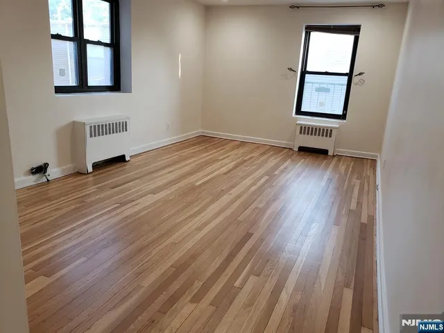 an empty room with windows and hardwood floor
