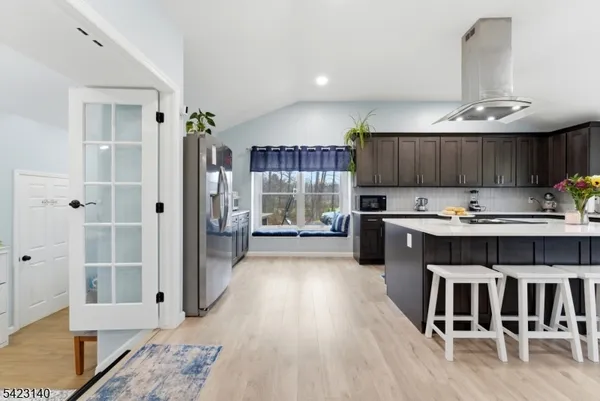 a kitchen with stainless steel appliances granite countertop a stove top oven a sink dishwasher and a cabinets with wooden floor