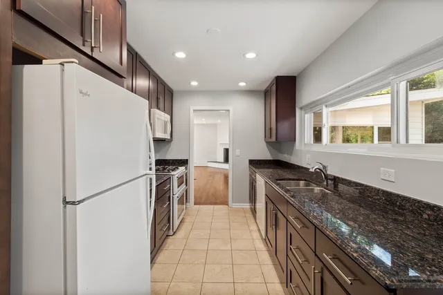 a kitchen with granite countertop a refrigerator stove and sink