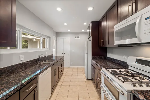 a kitchen with stainless steel appliances granite countertop a stove a sink and a microwave