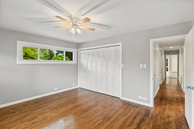 a view of an empty room with wooden floor and a chandelier