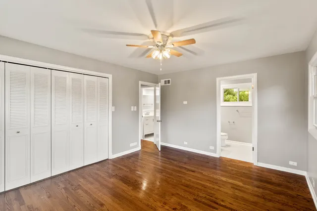 an empty room with wooden floor closet and windows