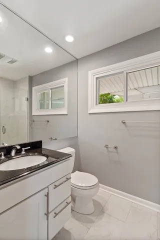 a bathroom with a granite countertop sink a toilet and a window