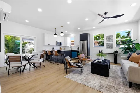 a living room with furniture kitchen view and a wooden floor