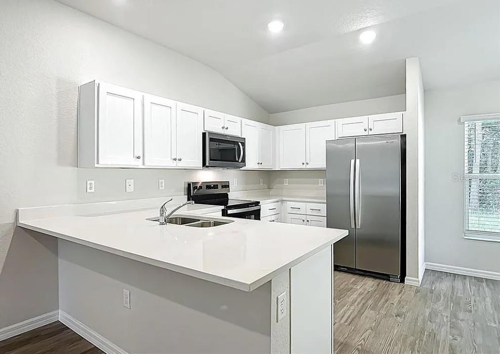 1145 South Apopka Avenue Inverness, FL 34452 - Photo 6 of 13 a kitchen with a refrigerator a microwave a sink and cabinets