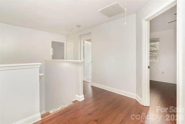 an empty room with wooden floor ceiling fan and window