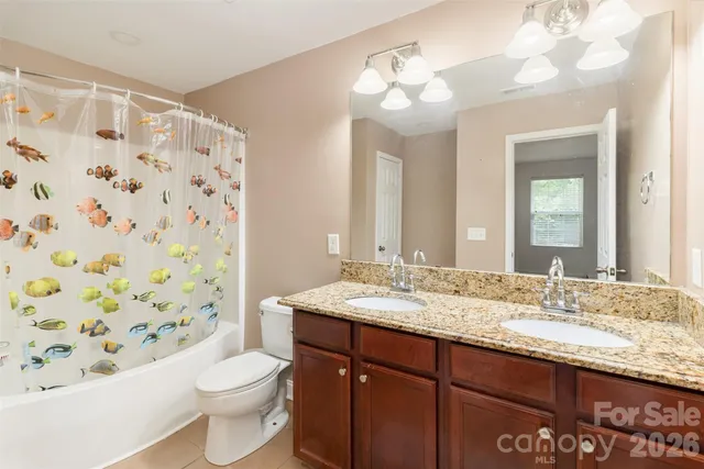a bathroom with a granite countertop sink toilet and mirror