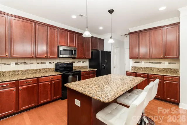 a kitchen with granite countertop wooden cabinets a stove a oven a dining table and chairs