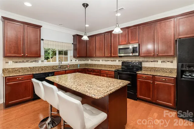 a kitchen with stainless steel appliances granite countertop wooden cabinets a stove a sink a refrigerator and a microwave