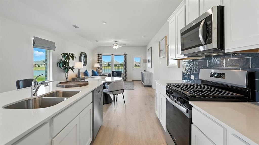 9820 Amalgam Street Aubrey, TX 76227 - Photo 22 of 40 a kitchen with stainless steel appliances a sink a stove and cabinets