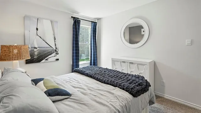 a bedroom with a bed lamp and a large window