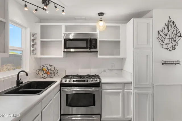 a kitchen with stainless steel appliances granite countertop a sink stove and microwave