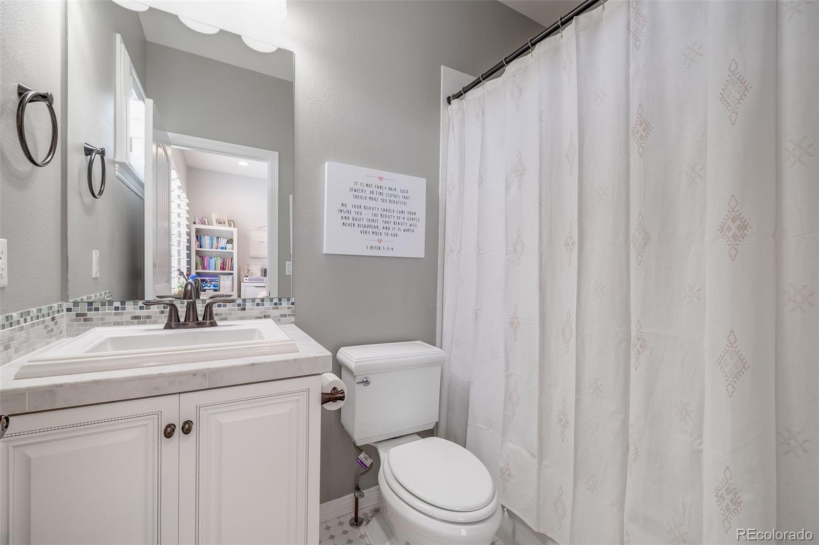 10702 Sundial Rim Road Highlands Ranch, CO 80126 - Photo 23 of 49 a bathroom with a sink a toilet a mirror and shower curtain