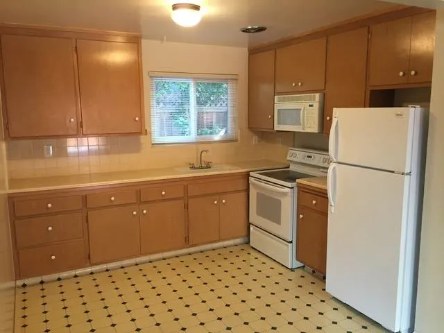 a kitchen with a sink a stove cabinets and a window