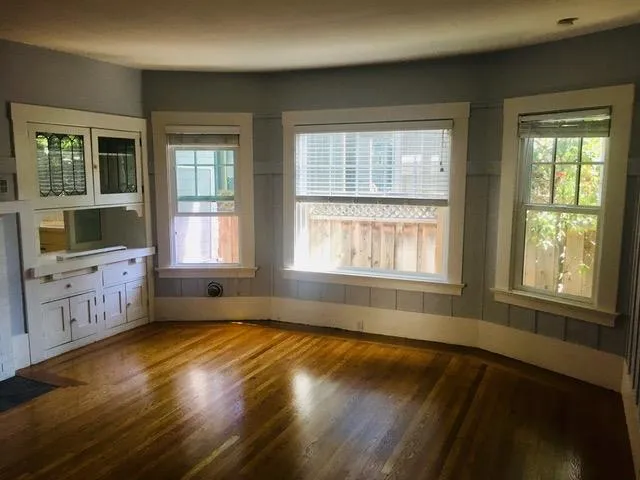 a view of an empty room with a window and wooden floor