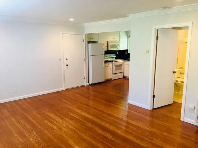 a view of a kitchen with wooden floor and a refrigerator