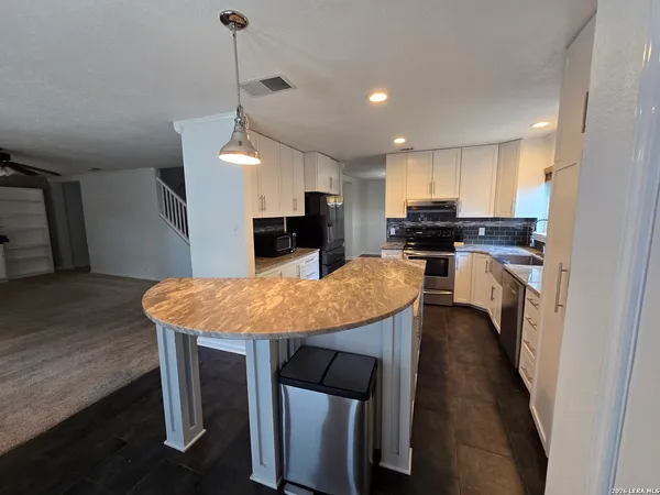 a kitchen with stainless steel appliances kitchen island granite countertop a stove a sink a refrigerator a center island with wooden floor and cabinets