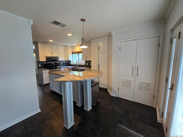 a kitchen with kitchen island a stove a sink a refrigerator and chairs