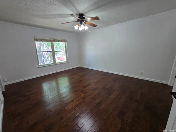 an empty room with wooden floor chandelier fan and windows