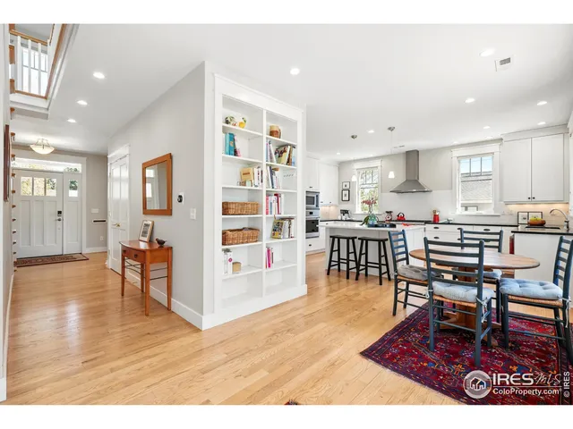 a living room with stainless steel appliances lots of furniture and wooden floor