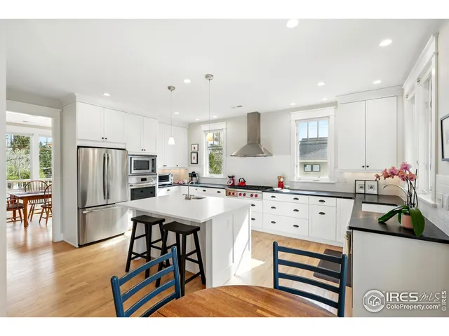 a kitchen with stainless steel appliances a stove a sink dishwasher a refrigerator white cabinets and wooden floor