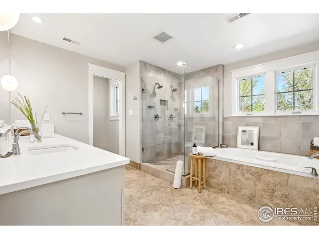 a bathroom with a tub a sink a mirror and a shower