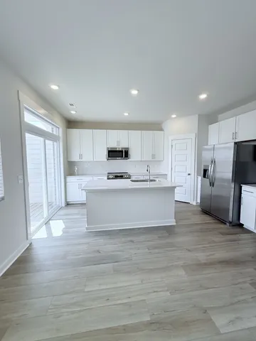 a large white kitchen with kitchen island a stove a cabinets and a sink