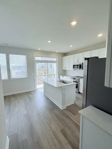 a kitchen with stainless steel appliances a sink a stove a microwave a sink a refrigerator wooden floor and cabinets