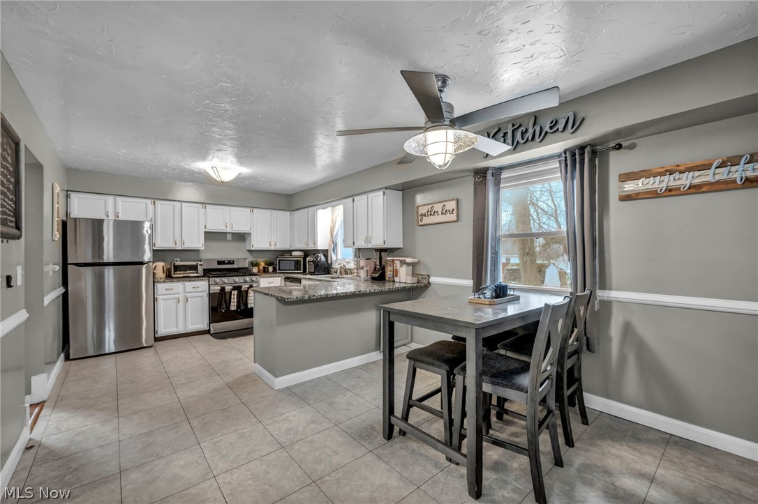 13800 Milo Road Garfield Heights, OH 44125 - Photo 13 of 39 Kitchen with stainless steel appliances, a peninsula, a textured ceiling, a ceiling fan, and white cabinets