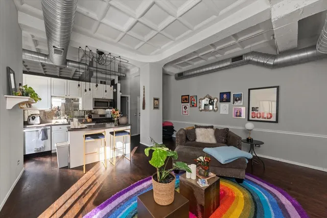 a living room with stainless steel appliances furniture and a kitchen view