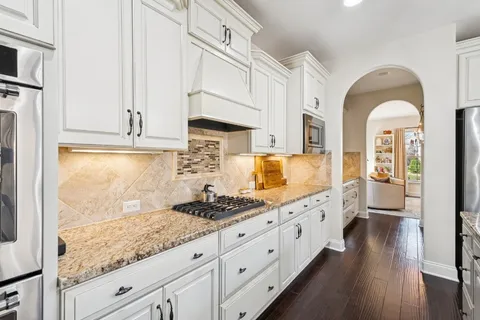 a kitchen with granite countertop a stove a sink and a refrigerator