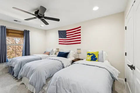 a bedroom with two beds and next to a window