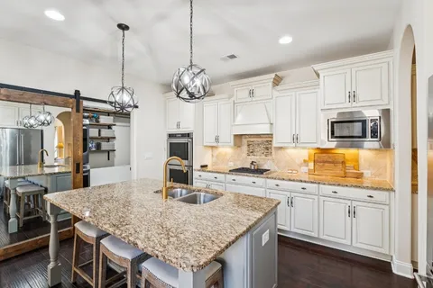 a kitchen with kitchen island granite countertop a sink a center island and cabinets