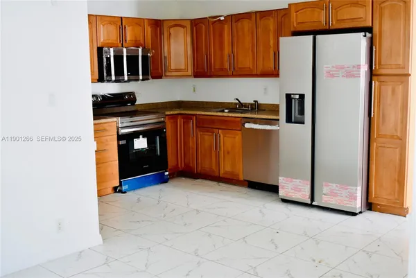 a kitchen with stainless steel appliances granite countertop a refrigerator a sink and dishwasher